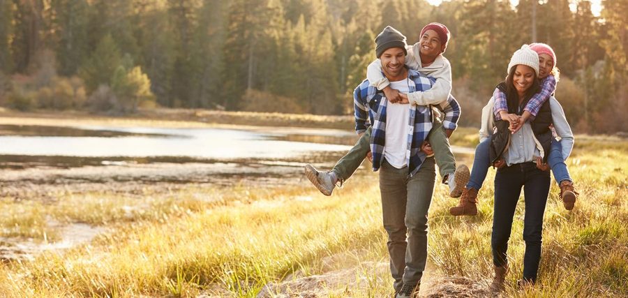 A family walking together outdoors on a grassy path beside water.