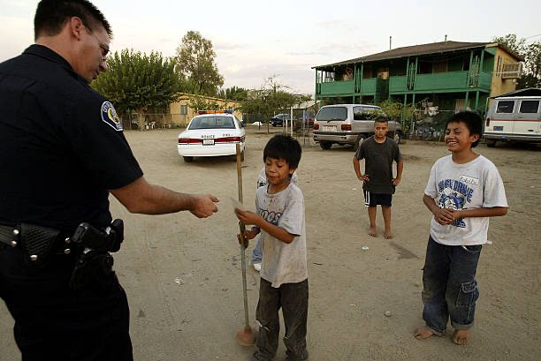 A police officer speaking with several children on a residential street.